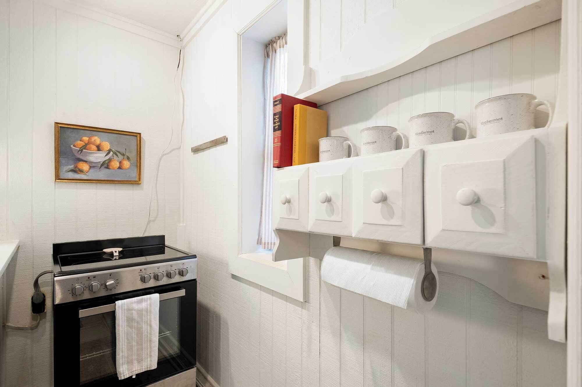 A kitchen with a stove, oven, and a wall-mounted spice rack with containers.
