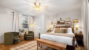A bedroom with a bed, a chair, a bench, a ceiling fan, and wall-mounted lamps. - Etowah Suite w Hot Tub, Family Stay Near Rock City (Lookout Mountain)