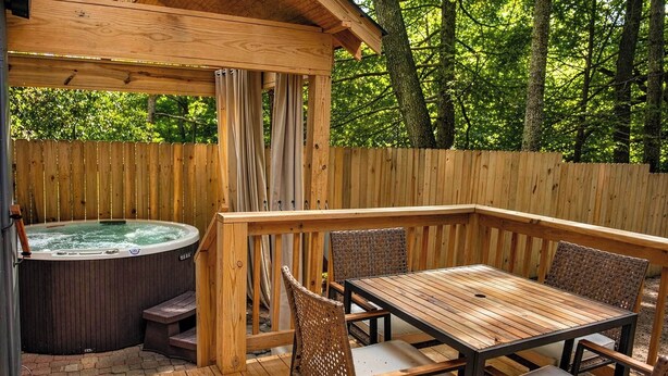 A wooden deck with a hot tub, a wooden table with chairs, and a wooden fence. - Etowah Suite w Hot Tub, Family Stay Near Rock City (Lookout Mountain)