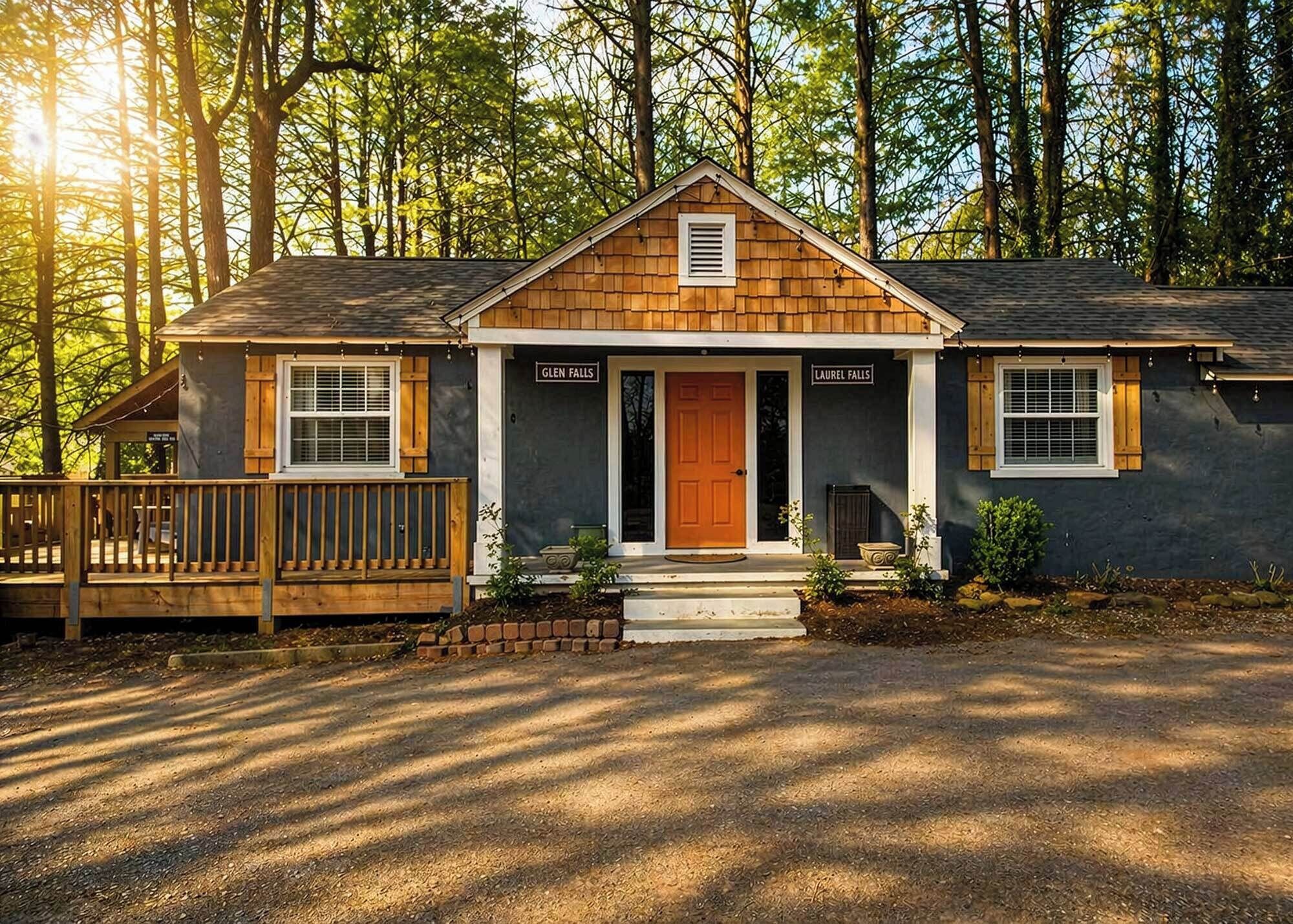 A cabin with a front porch, a wooden deck, and a mailbox.