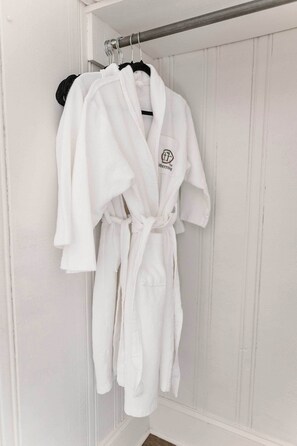 Un vestido blanco colgado en un perchero metálico en una habitación con paneles blancos.