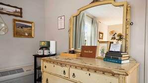 Een dressoir in vintage stijl met spiegel, een gastenboek en boeken.