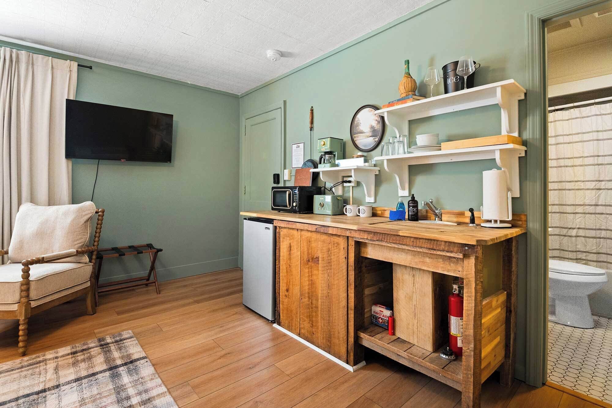 Una cocina compacta con encimera de madera, microondas, cafetera y refrigerador pequeño.