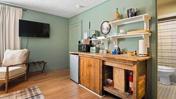 Una cocina compacta con encimera de madera, microondas, cafetera y refrigerador pequeño.