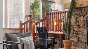 Una sala de estar acogedora con una escalera de madera, un cactus y una pared de piedra.