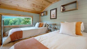 Une cabane avec deux lits, des murs en bois, une fenêtre donnant sur un paysage agréable et une étagère sur laquelle est posée une photo.