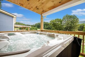 Ein Whirlpool mit Holzterrasse und Blick auf ein Haus und Bäume.