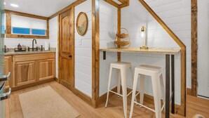 A kitchen with wooden accents, a window, and a sink. - The Honeycomb Cabin (Chattanooga)