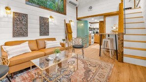 A cozy living room with a sofa, chairs, a coffee table, and a painting on the wall. - The Honeycomb Cabin (Chattanooga)