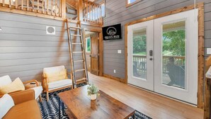 Ein Loft-Zimmer mit Holzbalkendecke, einem Schlafplatz in der Höhe, einem Esstisch, einer Couch und einem Schild für Quail Run Farm.