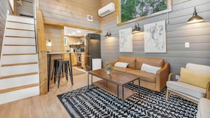 Ein modernes Interieur mit einer Holztreppe, einer Küchenzeile, einem Esstisch und einer Sofagarnitur.