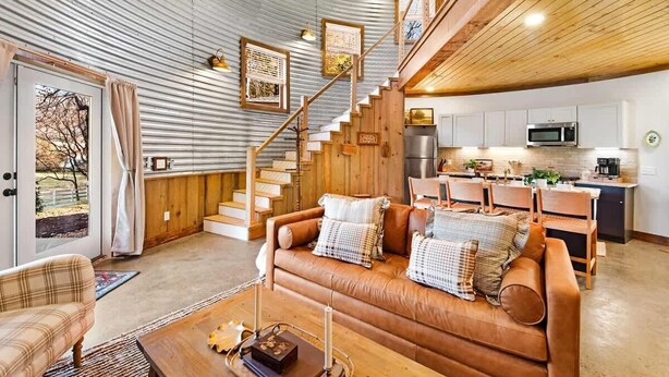 A cozy interior with a staircase, a wooden dining area, and a kitchen with modern appliances. - Lookout Silo with Mountain Views & Hot Tub (Chattanooga)