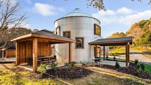 A rustic cabin with a cylindrical main building, wooden structures, and a well-maintained garden. - Lookout Silo with Mountain Views & Hot Tub (Chattanooga)