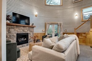 A cozy living room with a stone fireplace, a flat-screen TV, and a comfortable sofa. - Hollow Silo Stay with Pasture Views & Hot Tub (Chattanooga)