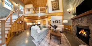 A spacious living area with a fireplace, a staircase, and a kitchen in the background. - Cozy Ridge Silo - Sleeps 6 with Private Hot Tub (Chattanooga)