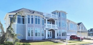 Un edificio residencial de varios pisos con balcón, ventanas amplias y garaje.