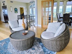 A spacious living area with wicker furniture, a large window, and a view of the outdoors. - 5 BR Waterfront - Boat Slips - Pool - Beach (Longport)