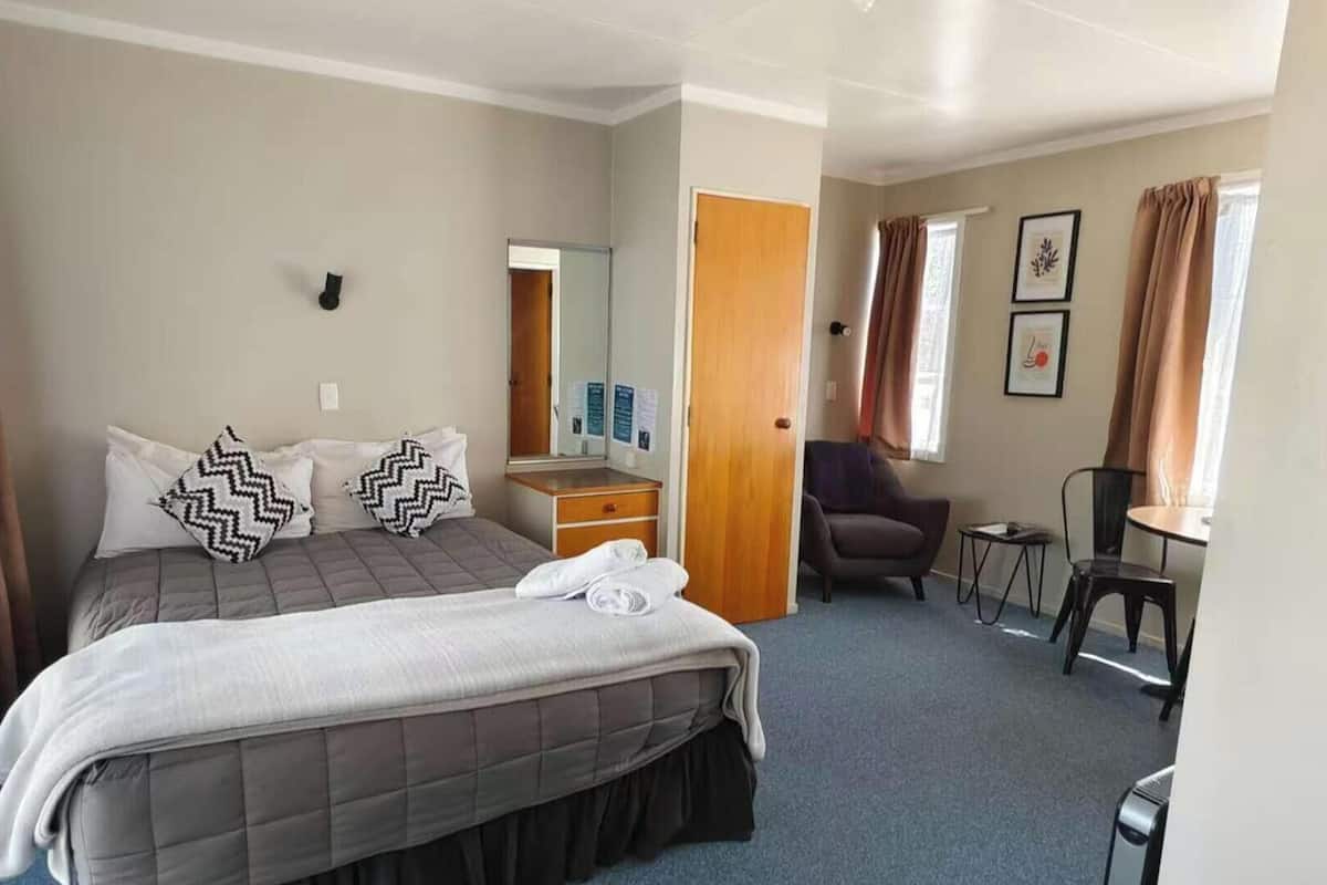 Una habitación de hotel con cama, escritorio, silla y una mesita.
