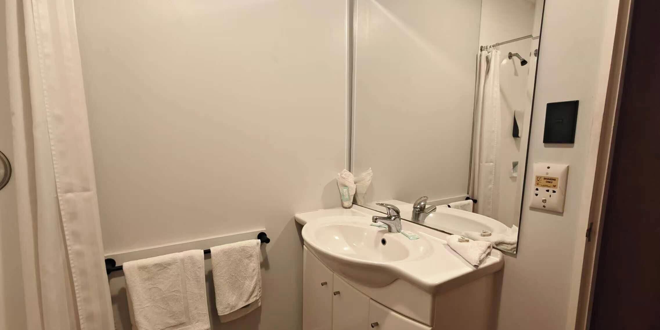 A bathroom with a white sink, a mirror, and two towels hanging on a rack.