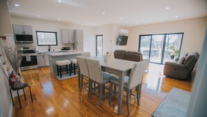A modern kitchen with a dining area, a sofa, and a large window. - The Creek House on Kaaterskill (Palenville)