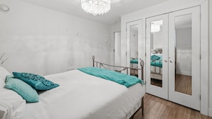 A bedroom with a bed, a chandelier, and a wardrobe with mirrored doors. - Modern Heritage Apartment in the Heart of Halifax (Halifax)