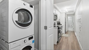 A laundry room with stacked washing machines and dryers, a microwave, and a small kitchenette. - Modern Heritage Apartment in the Heart of Halifax (Halifax)