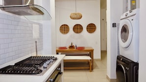 Una cucina moderna con piano cottura a gas, forno integrato, cappa aspirante in acciaio inossidabile e lavatrice a scomparsa.