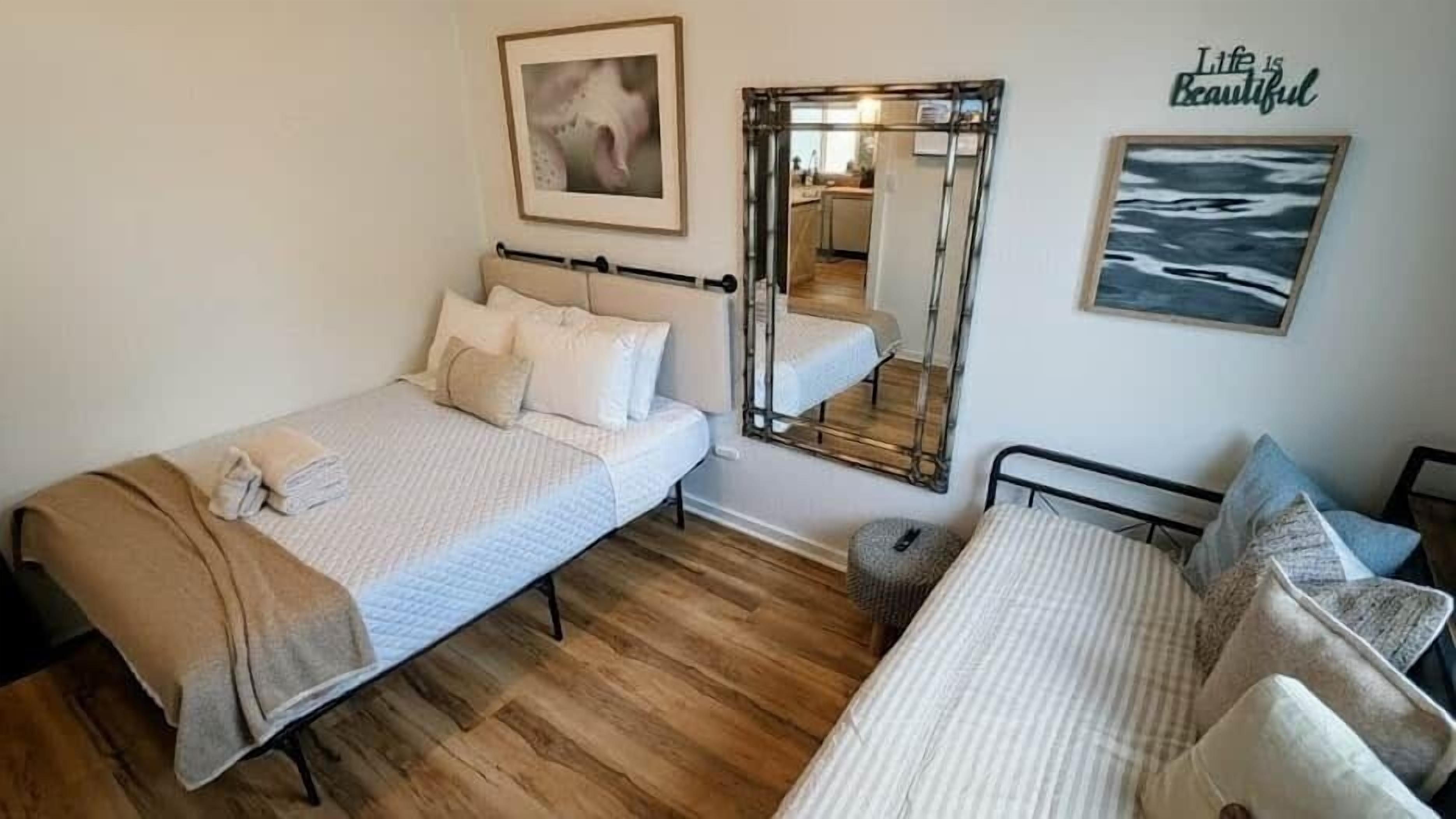 Una habitación con dos camas, un espejo y obras de arte en las paredes.