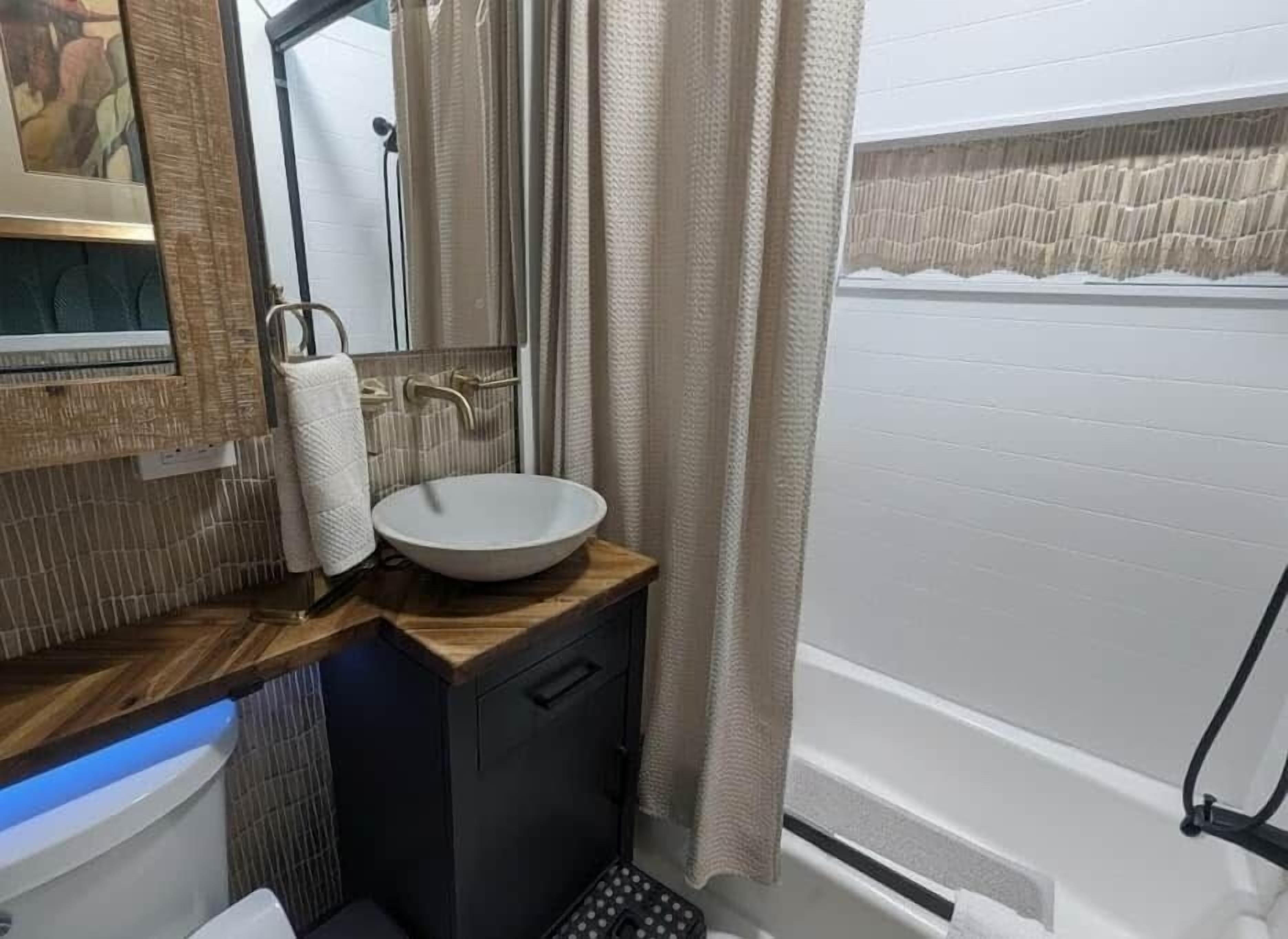 Une salle de bain équipée d’un lavabo, d’un miroir, d’un porte-serviettes et d’un rideau de douche.