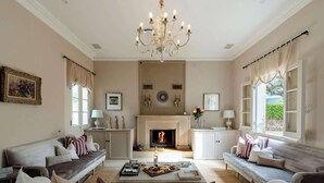 A spacious living room with a fireplace, sofas, and a chandelier. - One-of-a-Kind French Farm Stay in Kiama Hinterland (Jerrara)