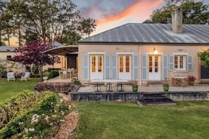 Ein Haus mit überdachter Terrasse, Sitzgelegenheiten im Freien und einem Garten.