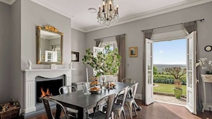 A dining room with a fireplace, a chandelier, and a view of the outdoors. - One-of-a-Kind French Farm Stay in Kiama Hinterland (Jerrara)