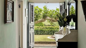 A hallway with a chandelier, a door leading to a garden, and a mirror on the wall. - One-of-a-Kind French Farm Stay in Kiama Hinterland (Jerrara)