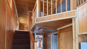A wooden staircase leading to a lofted area with a balcony. - Little Lantern Cabin (Indianapolis)
