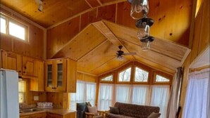 A wooden cabin interior with a kitchen, dining area, and living room. - Little Lantern Cabin (Indianapolis)