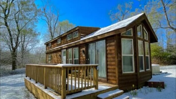 A wooden cabin with a deck, large windows, and a snow-covered ground. - Little Lantern Cabin (Indianapolis)