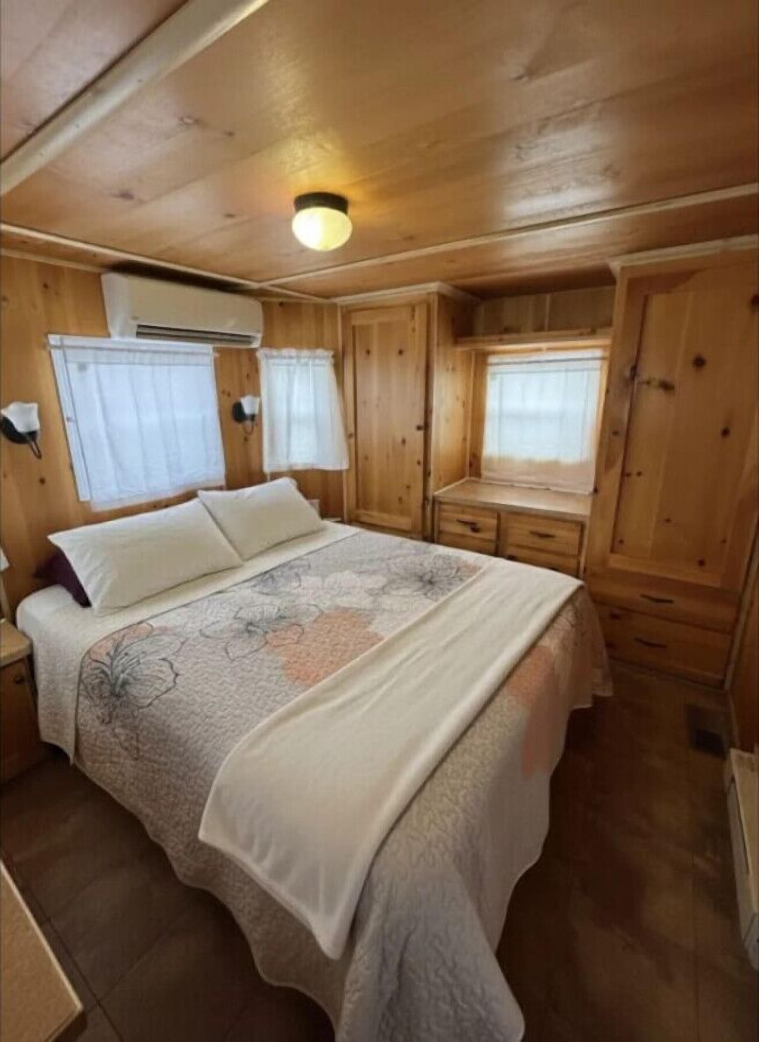 A cozy cabin-style bedroom with a bed, a dresser, and a window.