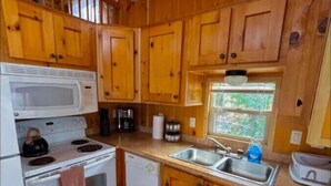 A compact kitchen with wooden cabinets, a microwave, stove, and a sink.