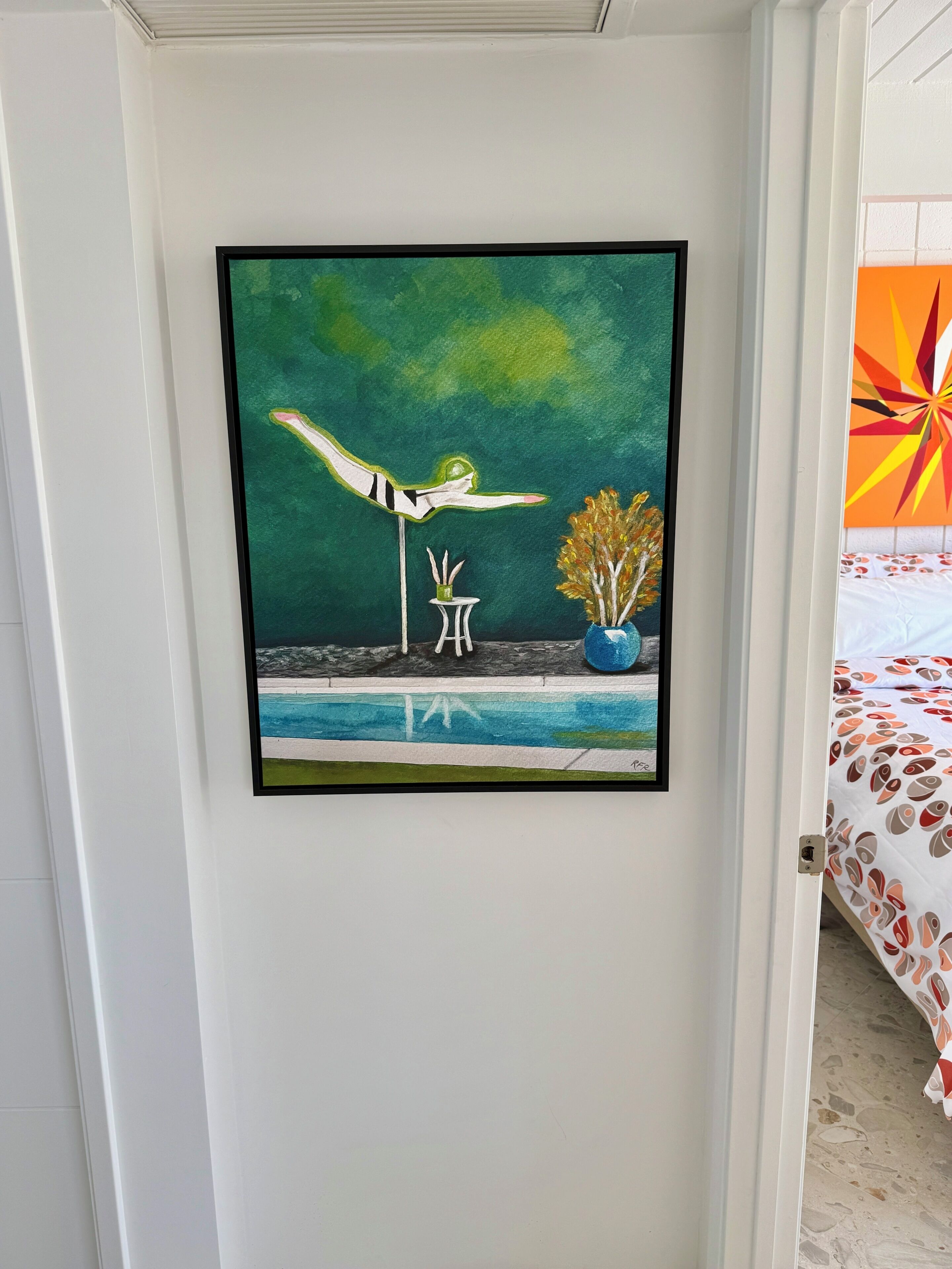 Un cuadro enmarco que muestra una figura en una pose dinámica, un taburete pequeño y un jarrón con flores secas sobre una pared.