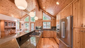 Une cuisine spacieuse dotée de meubles en bois, d’un réfrigérateur en acier inoxydable et d’un grand îlot central avec une cuisinière à gaz.