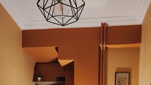Eine gemütliche Ecke mit einem schwarzen Sessel, einem kleinen Tisch mit Lampe und Regalen mit diversen Gegenst änden.