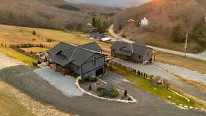 A rural property with two main buildings, a fenced yard, and a road leading to a red house. - Luxe | 8BR 6 Kings | Sleeps 22 | 2HotTub | Firepit (Banner Elk)