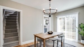 En matplats med ett träbord, fyra stolar, en kristallkrona och utsikt över omgivningen genom stora fönster.