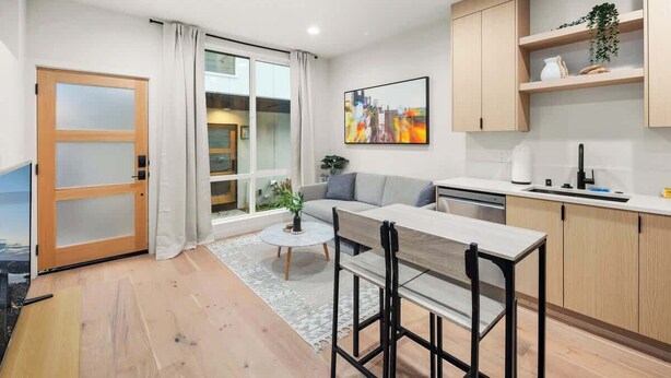 A modern kitchen with a dining area, a sofa, and a large window with curtains. - 2026 World Cup | Rooftop View, Light Rail, Parking (Seattle)