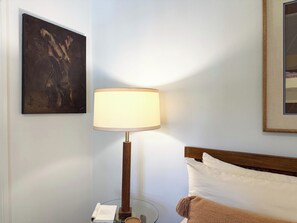 A hotel room with a bed, a bedside lamp, a framed picture on the wall, and a small table with a book and a phone. - the escape: king bedroom w/pool, hot tub access (Houston)