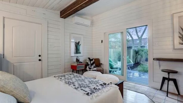 A bedroom with a bed, a nightstand, a chair, and a window.