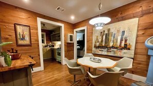 Uma cozinha moderna com paredes de madeira, uma área de jantar com mesa e cadeiras redondas, e um quadro grande na parede.