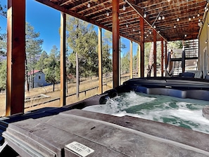 A hot tub under a wooden pergola with a view of trees and a small building. - Zia Peak (Ruidoso)