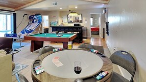 A pool table, a billiards table, and a dartboard in a room with wooden ceilings and a view of a bedroom. - Zia Peak (Ruidoso)