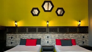 Una habitación de hotel con dos camas, una pared amarilla y apliques decorativos.